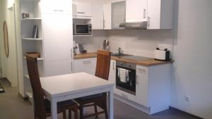 uma cozinha com armários brancos, uma mesa e um lavatório em Ferienwohnung Im Weihergrund em Engen