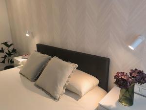 a white bed with two pillows and a vase of flowers at Kaioa in Ondárroa