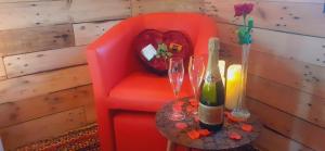 a red chair with a table with wine glasses and a heart pillow at La Grange in Verlaine