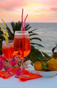 two wine glasses sitting on a table near the ocean at Hotel Sylesia in Letojanni