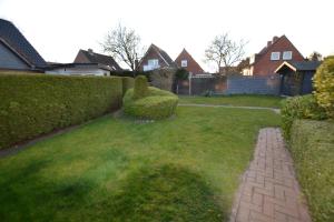 a yard with a hedge and a brick path at FeWo Landkirchen 2 in Fehmarn
