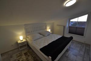 a bedroom with a bed with two lamps and a window at FeWo Landkirchen 2 in Fehmarn