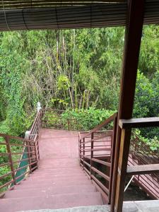 a wooden bridge over a walkway with trees at Indah Riverside Villa Yogyakarta in Piyungan +7 photos