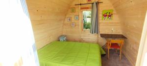 a small bedroom with a green bed and a desk at Pod in Camoël