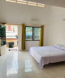a bedroom with a white bed and yellow curtains at Russian Market Bakery and Guesthouse in Phnom Penh