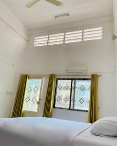 a bedroom with a bed and a window with yellow curtains at Russian Market Bakery and Guesthouse in Phnom Penh