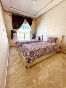 une chambre avec deux lits et une grande fenêtre dans l'établissement Les Jardins de Bouznika Premium - Votre espace familial, à Bouznika 8 autres photos