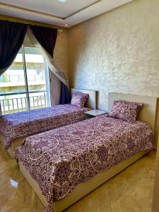 deux lits dans une chambre avec une fenêtre dans l'établissement Les Jardins de Bouznika Premium - Votre espace familial, à Bouznika