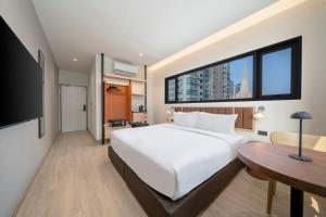 a bedroom with a bed and a desk and a large window at Asoka Hotel at Asoke Makkasan in Bangkok +53 photos