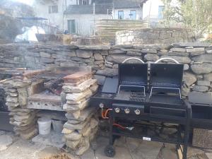 a grill with two chairs next to a stone wall at Casa Francesca in Cavigliano