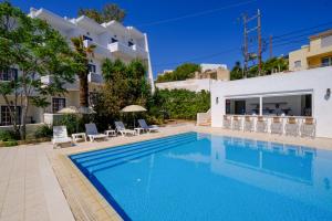 a pool in front of a house with chairs and a building at Athina Studios in Vathí