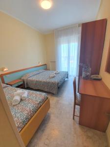 a hotel room with two beds and a desk at Hotel De La Plage in Rimini +39 photos