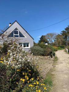 a white house with flowers in front of it at Maison 400m de la plage in Crozon