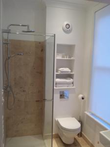 Un baño con ducha, WC y toallas. en Ogilvy House, en Cromer