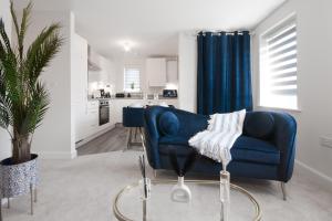 a living room with a blue couch and a kitchen at Flat in Milton Keynes Free parking Self checkin fast wifi in Milton Keynes
