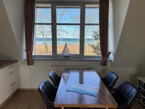 a dining room table with chairs and a large window at 2 Zimmer Appartement Ostseeblick in Boltenhagen