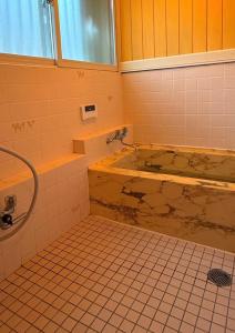a bathroom with a tub and a tiled floor at LAKE FOREST hug pug in Yamanakako