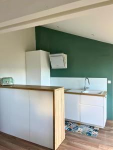 a kitchen with white cabinets and a sink at Maison familiale proche de la mer in Surtainville