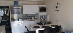 una cucina con mobili bianchi, tavolo e sedie di Zeepieper a Bredene