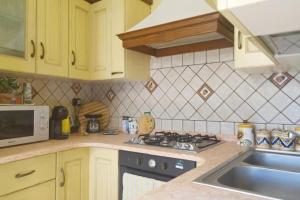 a kitchen with a stove top oven next to a sink at Dimora Pietra Antica in Milis