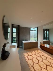 a bathroom with a tub and a sink and a mirror at Villa Odyssea Bergen NH in Bergen