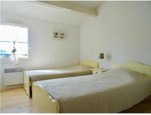 two beds in a white room with a window at Sunset in Saint-Jean-de-Monts