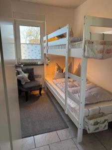 a bedroom with two bunk beds and a chair at !!!NEU!!! Bungalow Juist in Norddeich 150 m vom Strand in Norddeich