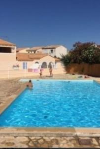 乐巴凯尔斯Superbe appartement terrasse piscine proche plage的一个大型蓝色游泳池,里面有人