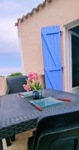 乐巴凯尔斯Superbe appartement terrasse piscine proche plage的一张带蓝色门的桌子，上面放着鲜花