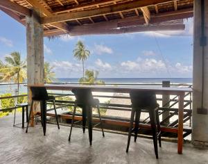 a table with chairs and a view of the beach at Katre Pacifico, Siargao - SELF CHECK-IN Budget Hostel in Pacifico, Siargao in San Isidro