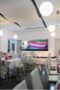 Hotel Baroca في مونتيريا: مطعم به طاولات وكراسي بيضاء وجدار ملون