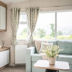 Una sala de estar con un sofá azul y una ventana. en Gimblet Rock Holiday Park, en Pwllheli