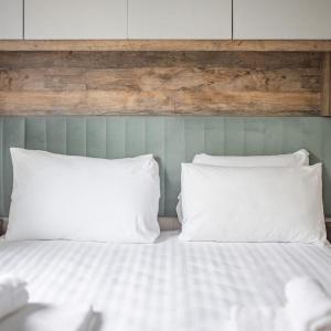 a bed with two white pillows and a wooden headboard at Gimblet Rock Holiday Park in Pwllheli