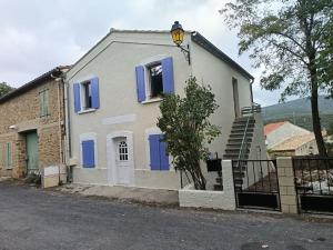 a white house with blue doors and a fence at Gîte lumineux avec jardin, vue sur Peyrepertuse in Rouffiac-des-Corbières