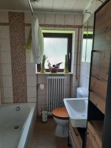 ein Badezimmer mit Badewanne, Toilette und Waschbecken in der Unterkunft Dörrs vacation home with pool and garden in Weißbach