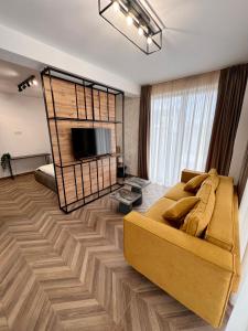 a living room with a yellow couch and a flat screen tv at MK Apart Boutique 2 in Voluntari