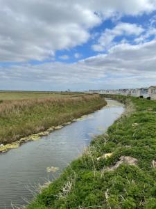 a river in the middle of a field at Beach Bay Holiday Home in Camber
