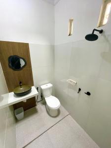 a white bathroom with a toilet and a shower at Sejiwa Homestay Syariah in Diyeng +25 photos
