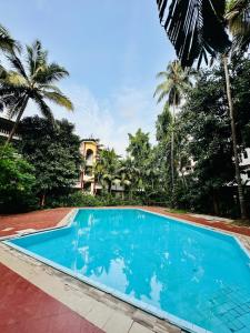 Una piscina frente a un resort con palmeras. en Pool facing Studio in Calangute, en Arpora