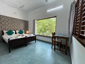 a bedroom with a bed and a window and a table at Coramandal Heritage in Puducherry