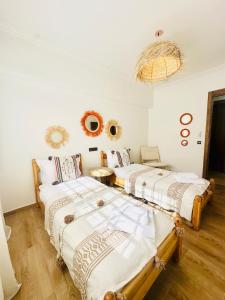 two beds in a room with white walls and wooden floors at Charmant Appartement 2 Room Wifi Marrakech in Marrakesh +4 photos