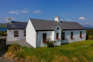 a white house on the side of a hill at Old Stones Cottage in Portmagee