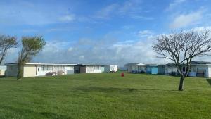 a group of buildings in a yard with a tree at Beach Bay Holiday Home in Camber