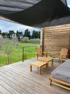 a wooden deck with two chairs and a couch on it at Tiny Housse à la campagne in Sarrians
