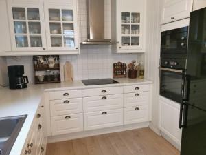 a kitchen with white cabinets and a black refrigerator at Unikt og romslig hus perfekt for grupper in Nordfjordeid