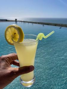 a hand holding a drink with a slice of lemon at Villa La Falaise in Oualidia