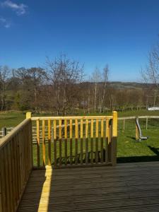 a wooden deck with a fence on a field at Country Cabin in Hesket Newmarket