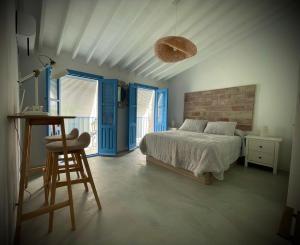 a bedroom with blue doors and a bed and a chair at Casa Alta 22 in Frigiliana