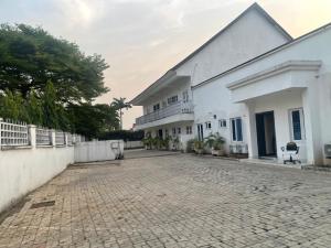 a large white building with a brick driveway at Ibiyemi apartment in Abuja