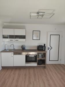 a kitchen with white cabinets and a sink and a stove at Sonniges und modernes Apartment Casa Nobi in Gebenbach